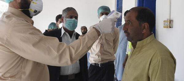 Врач проверяет температуру тела мужчины, возвращающегося из Ирана в карантинную зону, для проверки на коронавирус COVID-19 - Sputnik Таджикистан