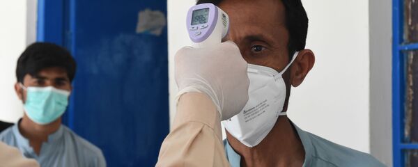 Врач проверяет температуру тела мужчины, возвращающегося из Ирана в карантинную зону, для проверки на коронавирус COVID-19 - Sputnik Тоҷикистон