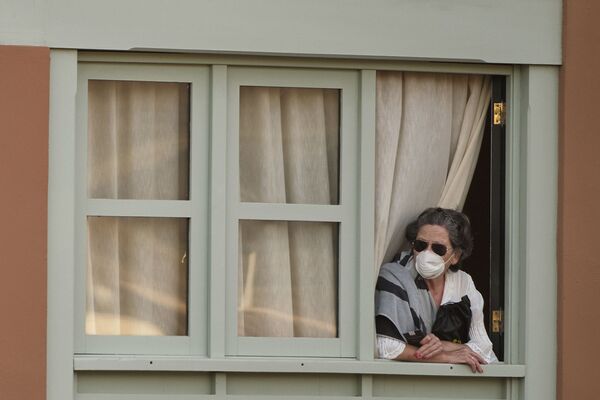 Женщина смотрит из окна Costa Adeje Palace hotel на Тенерифе - Sputnik Тоҷикистон