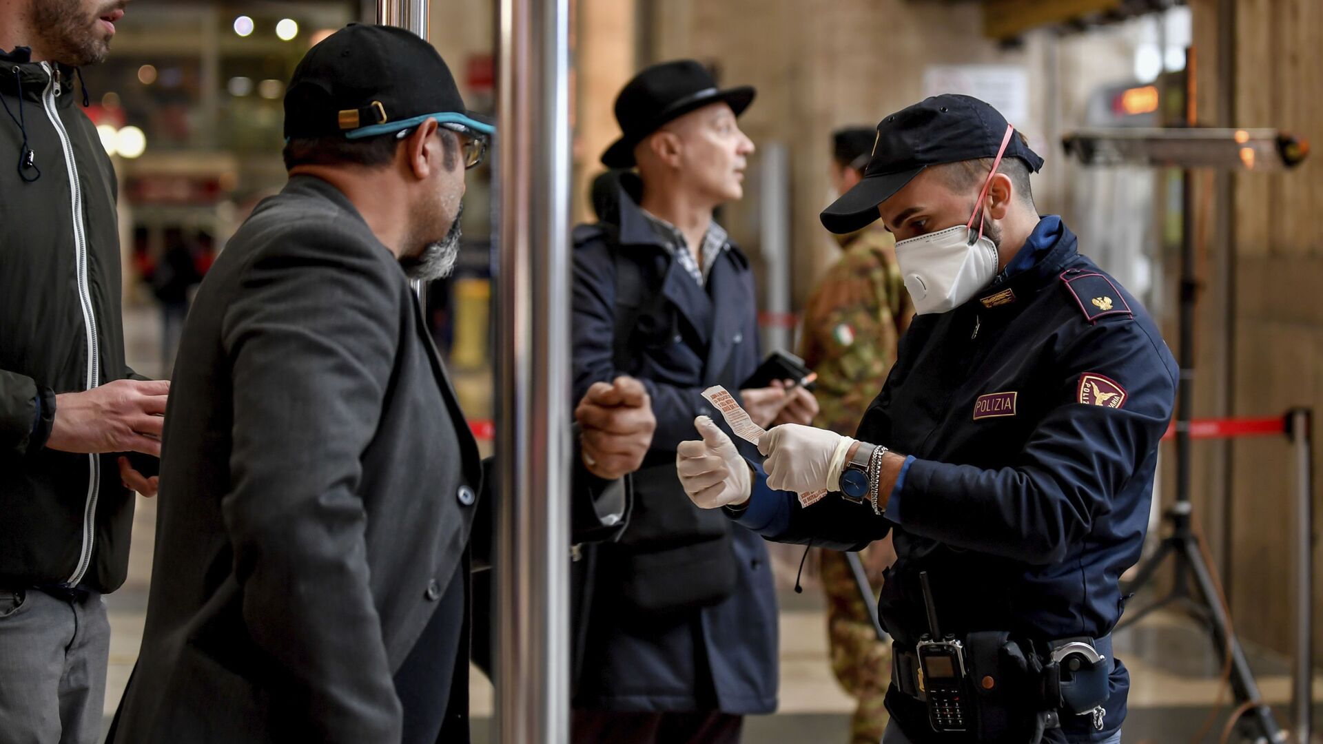 Полицейский в маске проверяет пассажиров, покидающих главный железнодорожный вокзал Милана - Sputnik Таджикистан, 1920, 28.11.2021
