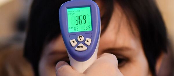 Женщине измеряют температуру в связи с угрозой распространения коронавирусной инфекции. - Sputnik Таджикистан