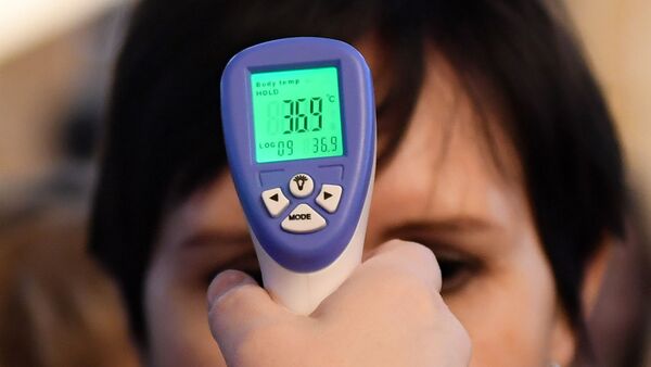 Женщине измеряют температуру в связи с угрозой распространения коронавирусной инфекции. - Sputnik Таджикистан