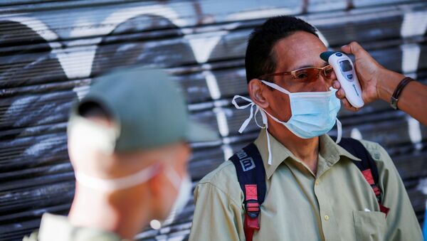 Мужчине в защитной лицевой маске измеряют температуру - Sputnik Таджикистан