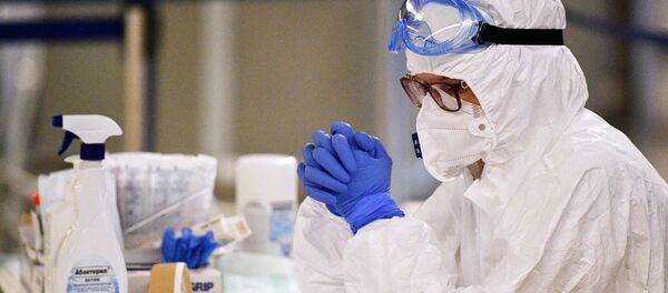 Медицинский работник в аэропорту в защитном костюме - Sputnik Тоҷикистон