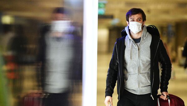 Молодой человек в медицинской маске в аэропорту - Sputnik Тоҷикистон