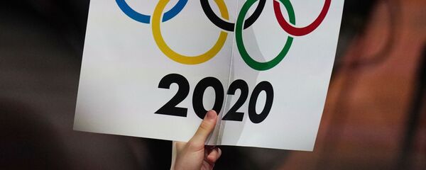 Журналист держит плакат с олимпийскими кольцами  - Sputnik Тоҷикистон