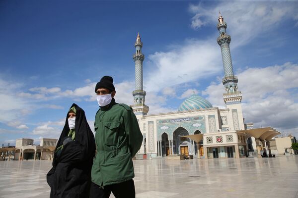 Пара в защитных пасках на улице в иранском городе Кум - Sputnik Таджикистан