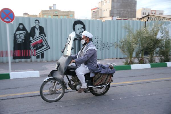 Мужчина в защитной маске едет на мотоцикле по улице в Иране - Sputnik Таджикистан