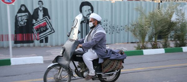 Мужчина в защитной маске едет на мотоцикле по улице в Иране - Sputnik Тоҷикистон