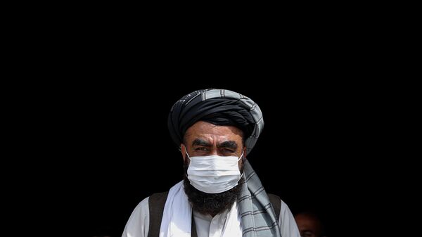 Мужчина в медицинской маске во время бесплатной раздачи продовольствия нуждающимся в Кабуле - Sputnik Тоҷикистон