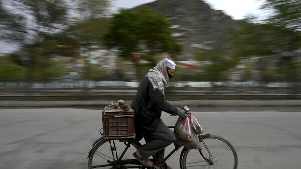 Мужчина в защитной маске едет на велосипеде по Кабулу, Афганистан - Sputnik Тоҷикистон
