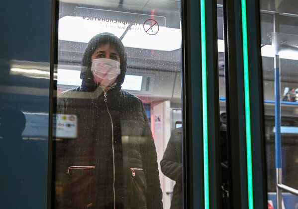 Женщина в защитной маске в вагоне поезда на станции метро Новокузнецкая в Москве - Sputnik Тоҷикистон