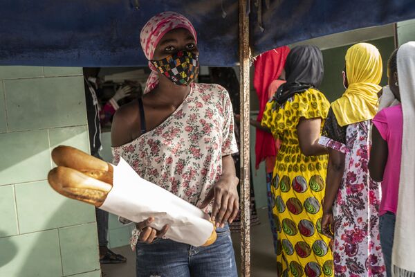 Девушка в маске покупает хлеб для своей семьи в первый день священного для мусульман месяца Рамадан в Дакаре, Сенегал - Sputnik Таджикистан