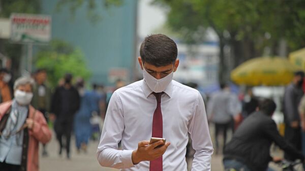 Мужчина в маске смотрит на телефон - Sputnik Таджикистан