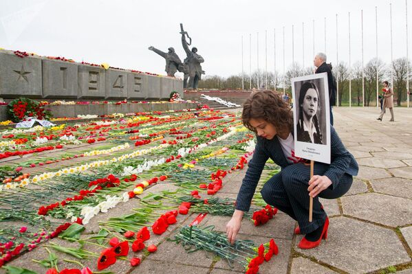 Организатор Бессмертного полка Маргарита Драгиле пришла к памятнику Освободителям с портретом бабушки-блокадницы (9 мая 2020). Латвия - Sputnik Таджикистан