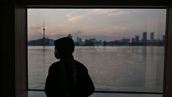 Человек в маске едет на пароме через реку Янцзы в Ухане, Китай - Sputnik Таджикистан