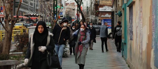Жители Тегерана идут по одной из центральных улиц в медицинских масках. Жители Тегерана идут по одной из центральных улиц в медицинских масках. - Sputnik Тоҷикистон