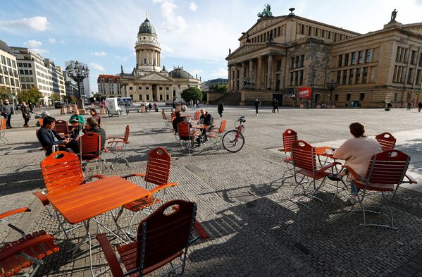 Люди наслаждаются погодой в кафе на площади Жандарменмаркт в Берлине, соблюдая при этом принцип социальной дистанции - Sputnik Таджикистан