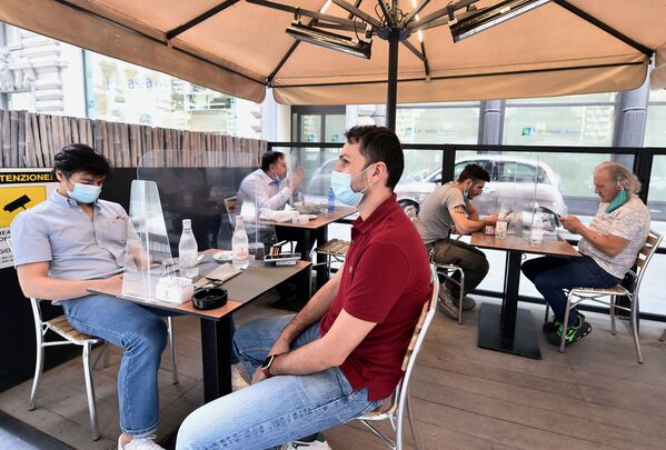 Люди в защитных масках сидят на террасе ресторана в Милане, Италия - Sputnik Таджикистан