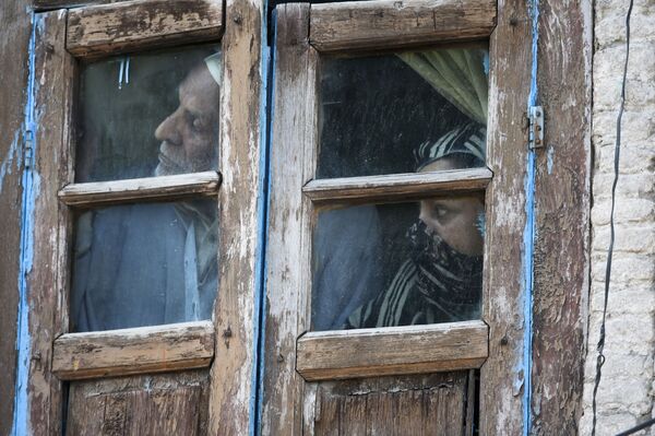 Люди смотрят из окна своего дома в Сринагаре, Индия - Sputnik Таджикистан