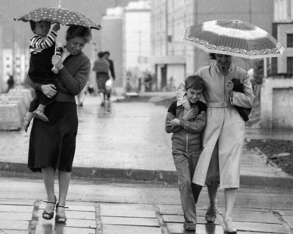 Прохожие идут по улице, прячась от дождя под зонтом. - Sputnik Таджикистан
