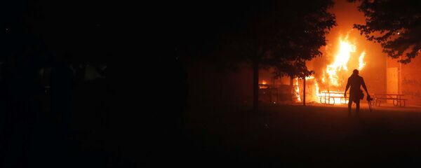 Фотожурналист уходит от горящего банка «Уэллс Фарго» во время протестов в США Фотожурналист уходит от горящего банка «Уэллс Фарго» во время протестов в США - Sputnik Таджикистан