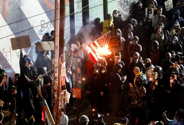 Протестующие сжигают американский флаг во время акции протеста против расового неравенства в Сиэтле - Sputnik Таджикистан