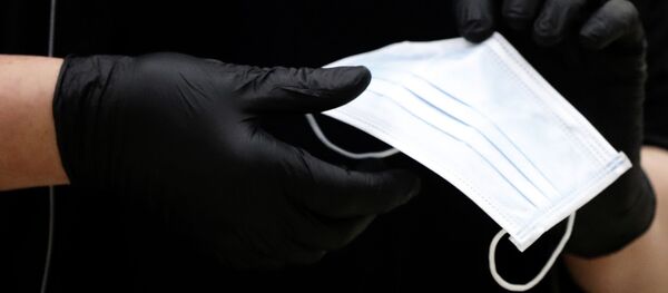 Человек в перчатках держит защитную медицинскую маску - Sputnik Таджикистан