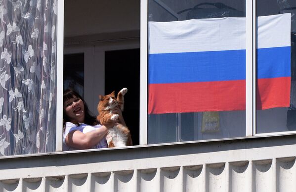Жительница Красноярска смотрит выступление музыкального ансамбля в День России из окна своей квартиры - Sputnik Таджикистан