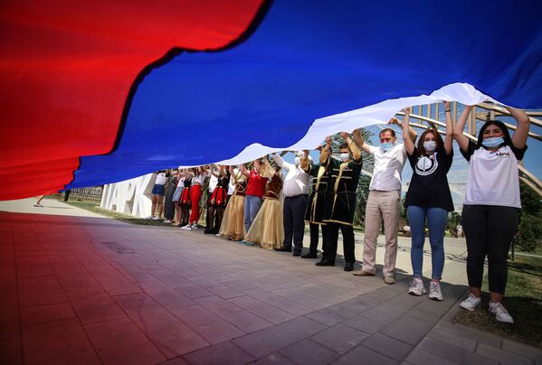 Участники празднований Дня России держат российский флаг в парке Дружбы города Георгиевска Ставропольского края - Sputnik Таджикистан