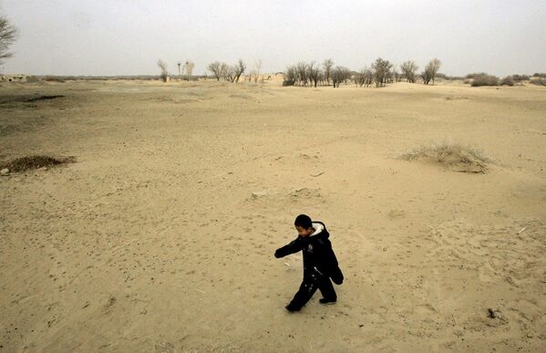 Ребенок идет по песчаной дюне в Вайси, китайская провинция Ганьсу, где нерациональное земледелие привело к опустыниванию - Sputnik Таджикистан