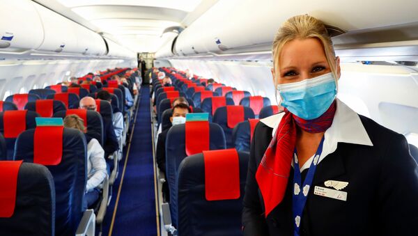 Стюардесса в медицинской маске в салоне самолета в международном аэропорту Брюсселя - Sputnik Тоҷикистон