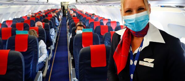Стюардесса в медицинской маске в салоне самолета в международном аэропорту Брюсселя - Sputnik Таджикистан