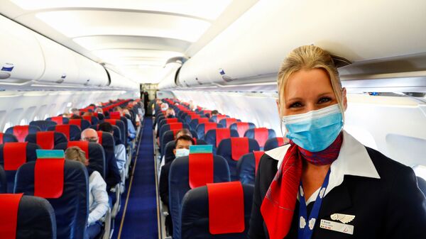 Стюардесса в медицинской маске в салоне самолета в международном аэропорту Брюсселя - Sputnik Таджикистан