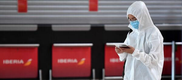 Пассажир, одетый в защитный костюм, ждет после регистрации на рейс в Пекине - Sputnik Тоҷикистон