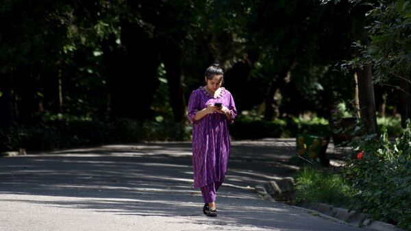Девушка смотрит в телефон прогуливаясь в саду Ирам - Sputnik Таджикистан