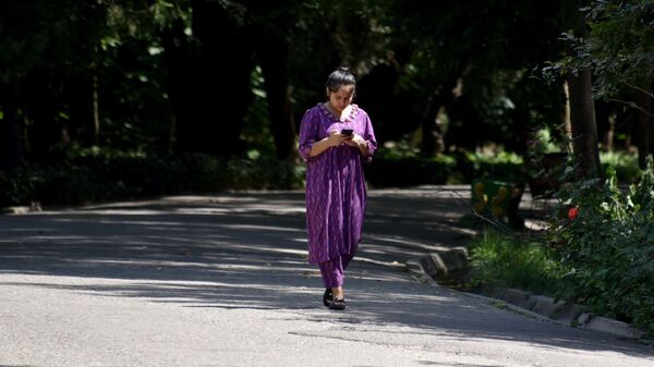 Девушка смотрит в телефон, прогуливаясь в саду Ирам - Sputnik Таджикистан